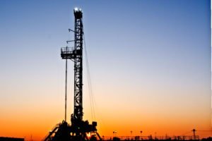 Landscape view of an oil drilling rig at sunrise.